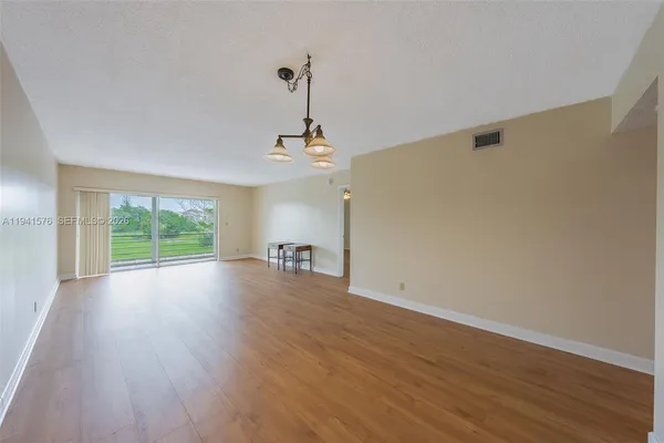 a view of a livingroom with wooden floor a ceiling fan and windows