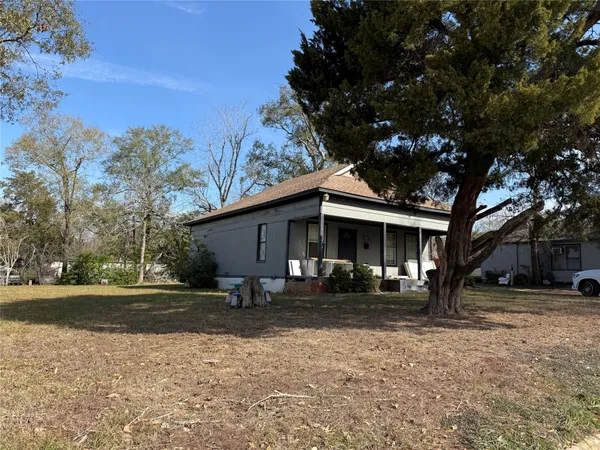 a front view of house with yard and trees in the background