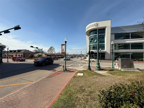 a front view of a building with cars parked on road