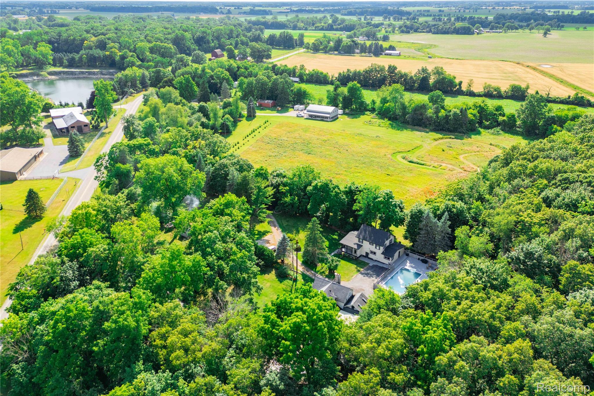 4860 Blue Bush Road Monroe, MI 48162 - Photo 49 of 59 Aerial perspective showcasing a sprawling property featuring a main residence, an outdoor swimming pool, extensive green spaces, mature tree coverage, and a paved driveway