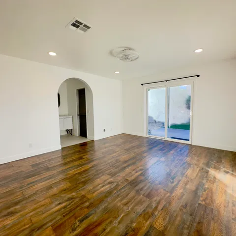 an empty room with wooden floor and natural light