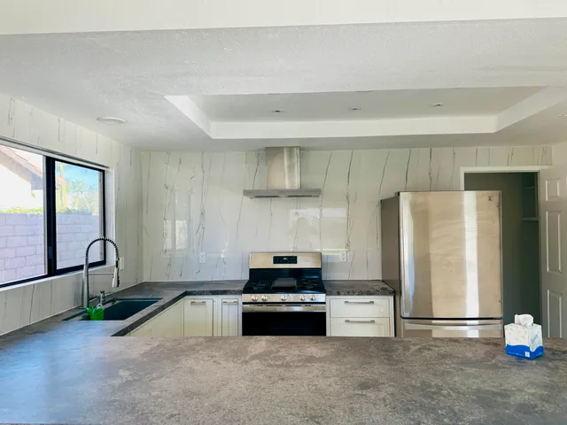 a kitchen with granite countertop a refrigerator and a stove top oven