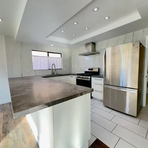 a kitchen with stainless steel appliances granite countertop a refrigerator a stove a sink and a microwave