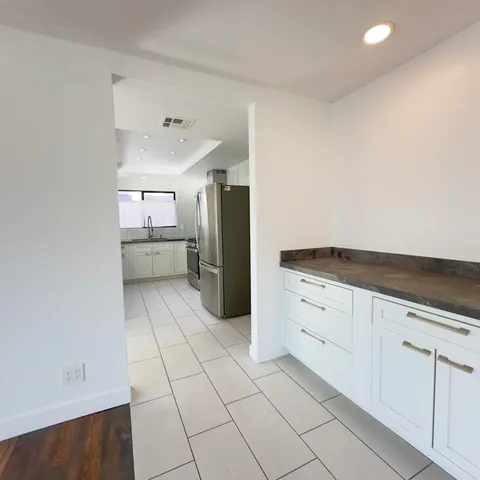 a kitchen with a refrigerator and white cabinets