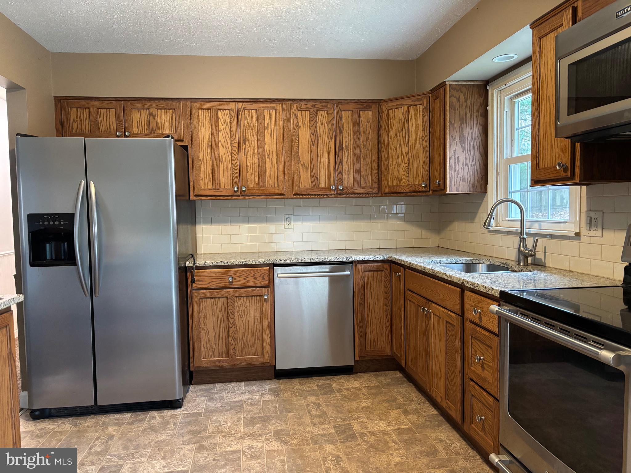 2213 Green Haven Way Hampstead, MD 21074 - Photo 10 of 15 a kitchen with stainless steel appliances granite countertop a refrigerator a sink a stove a microwave and island