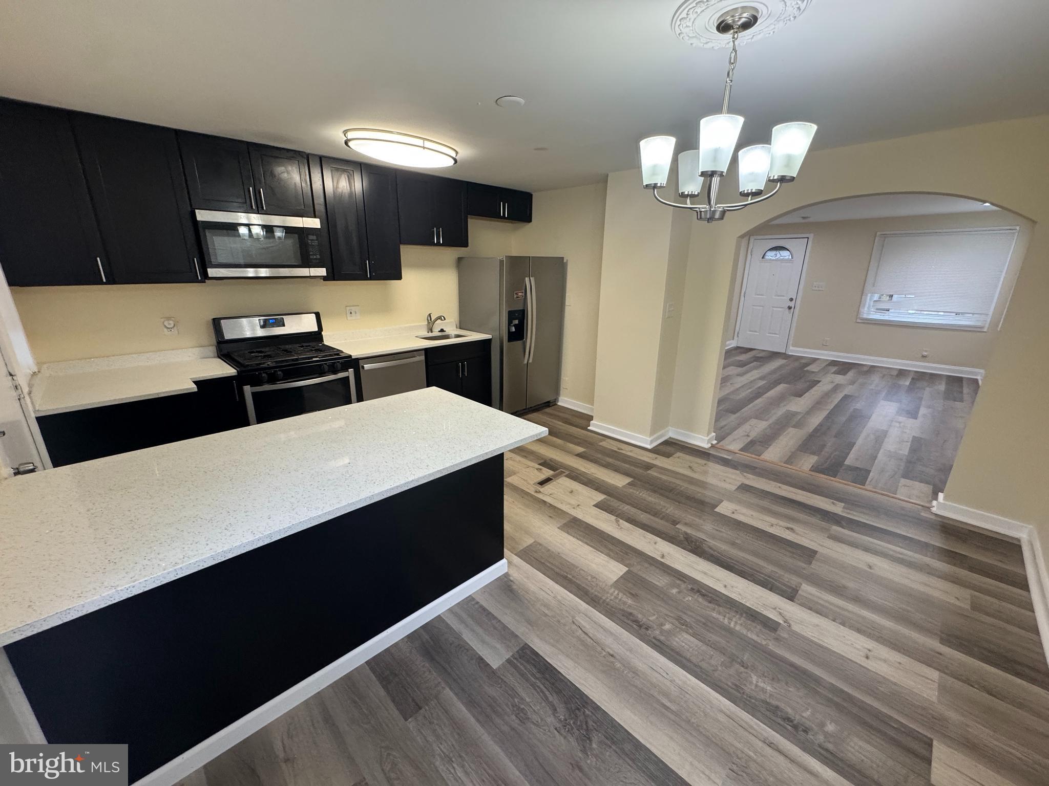 7445 Edsworth Road Baltimore, MD 21222 - Photo 8 of 37 a large kitchen with stainless steel appliances a large counter top space a sink a stove and refrigerator