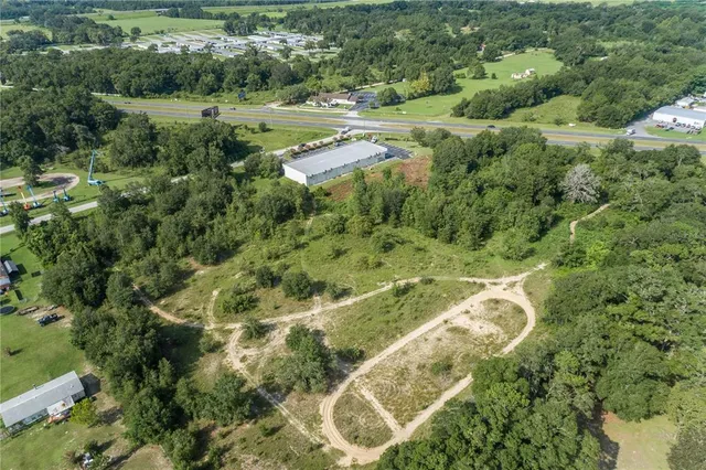 an aerial view of residential houses with outdoor space and trees