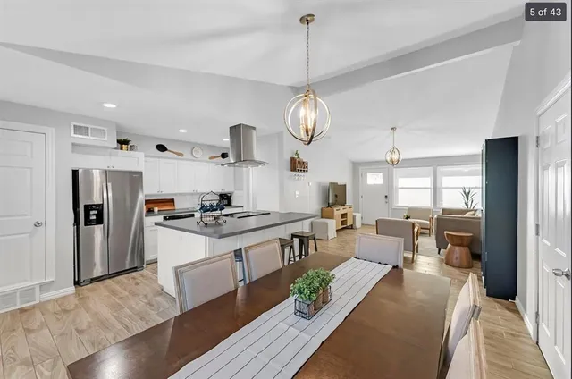 a kitchen with stainless steel appliances granite countertop a stove refrigerator and couches with wooden floor