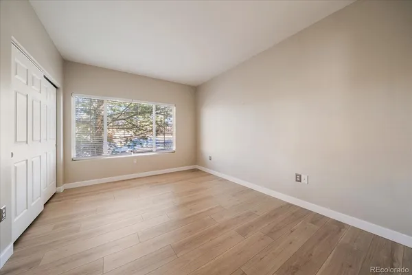 a view of an empty room with wooden floor and a window