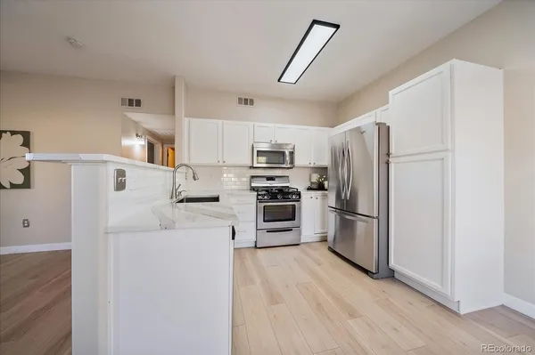 a kitchen with white cabinets and stainless steel appliances
