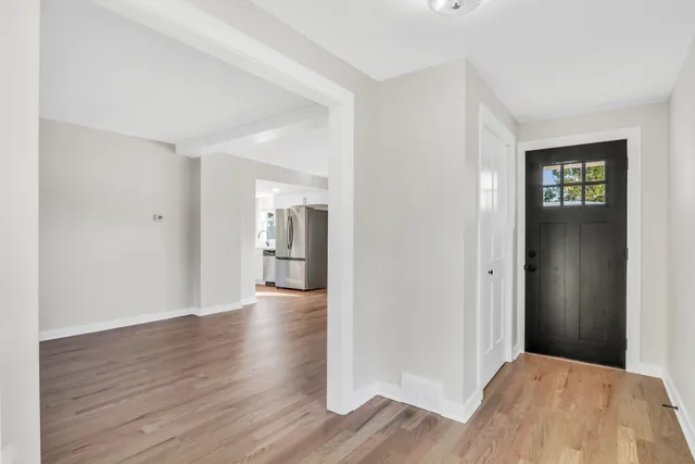 a view of an empty room with wooden floor and a window