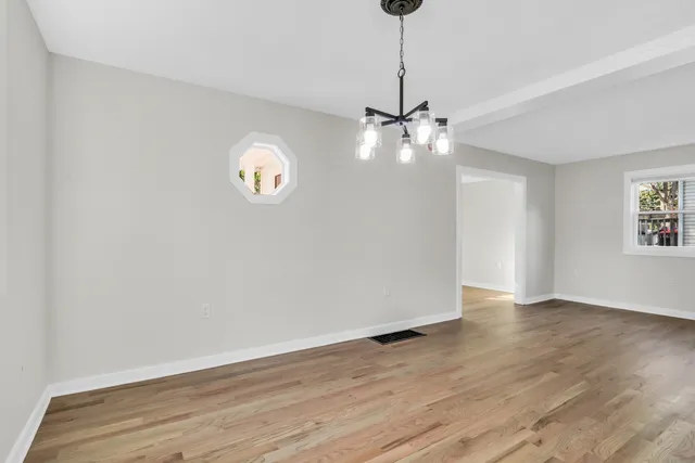 a view of an empty room with window and wooden floor