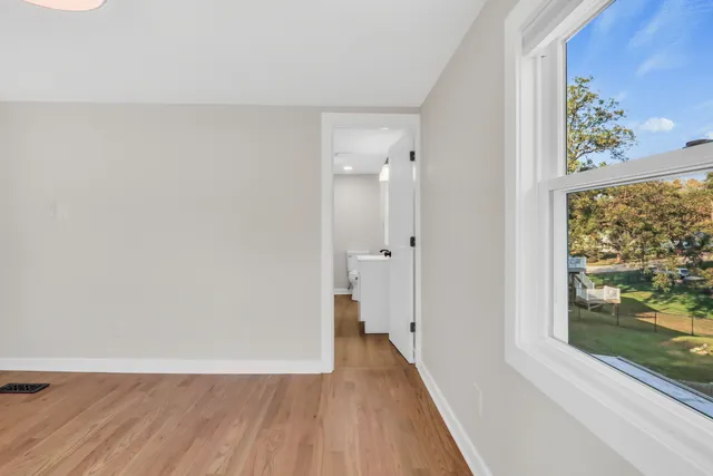 a view of a hallway with wooden floor and a bathroom
