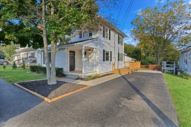 a view of a white house with a yard and large tree