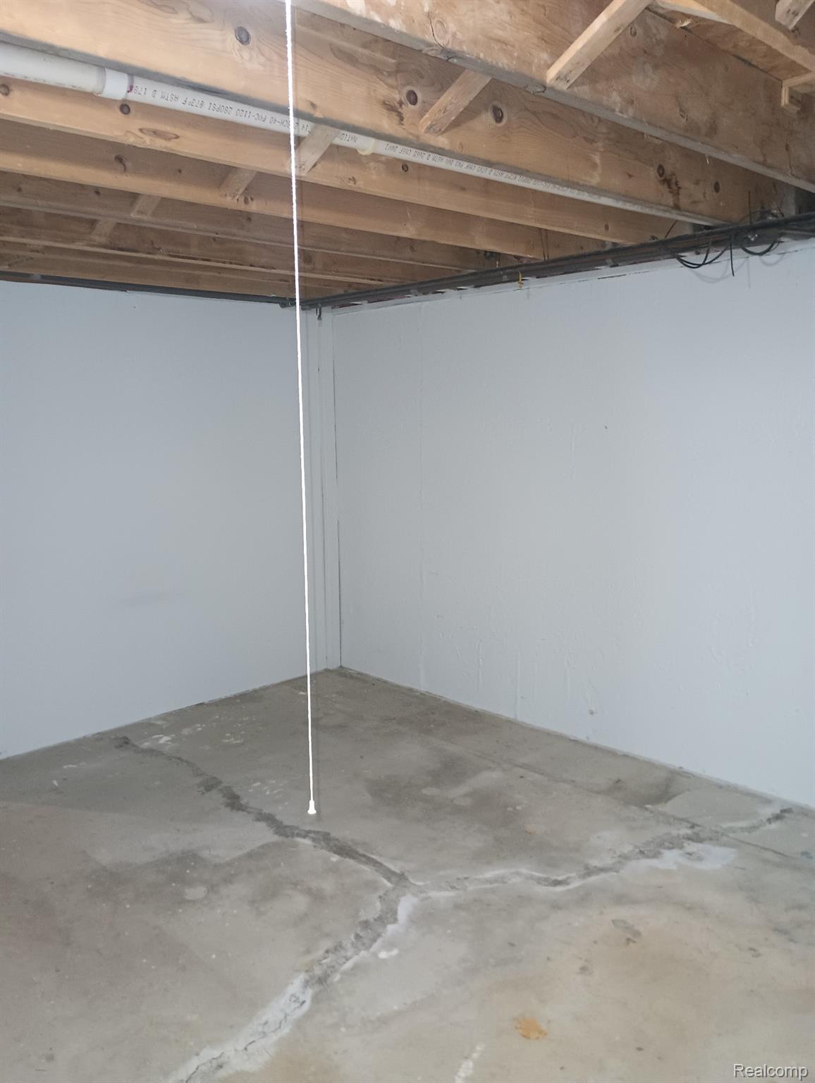 Unfinished basement space featuring exposed wood joists and concrete flooring