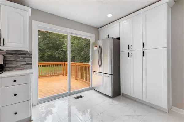 a large kitchen with stainless steel appliances granite countertop a stove a sink dishwasher a refrigerator and white cabinets with wooden floor