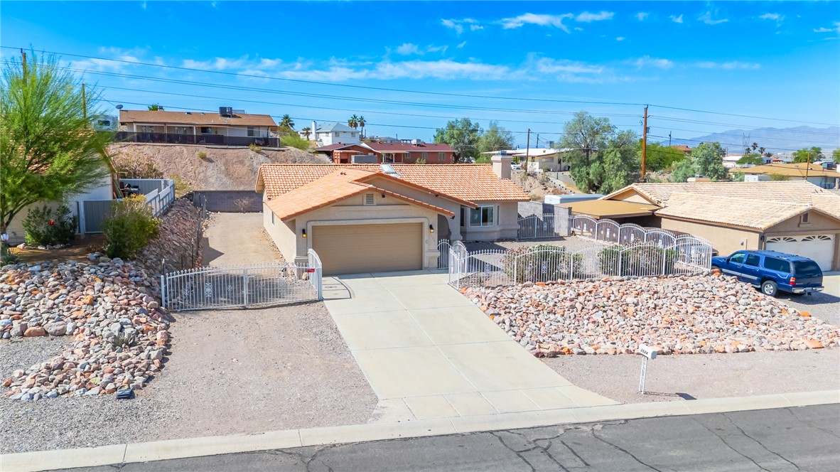 2524 South Ridge Avenue Bullhead City, AZ 86429 - Photo 64 of 64 Ranch-style house with concrete driveway, a fenced front yard, an attached garage, stucco siding, and a tiled roof