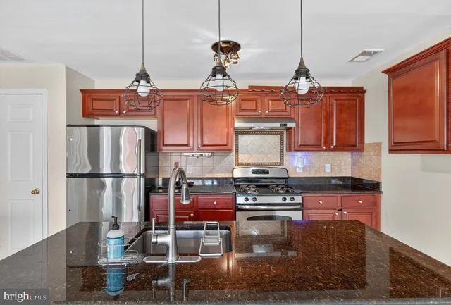 a kitchen with stainless steel appliances granite countertop a stove refrigerator and cabinets