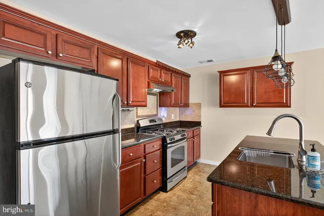a kitchen with granite countertop a refrigerator stove and sink