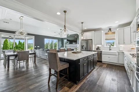 a kitchen with stainless steel appliances a dining table chairs and wooden floor