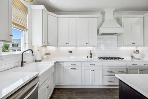 a kitchen with stainless steel appliances kitchen island granite countertop a dining table chairs and white cabinets