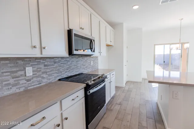 a kitchen with granite countertop wooden cabinets stove top oven and sink