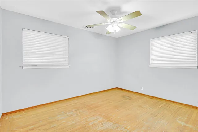 a view of a big room with wooden floor and chandelier fan