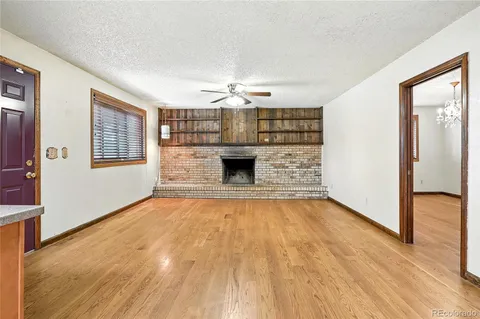 an empty room with wooden floor fireplace and windows