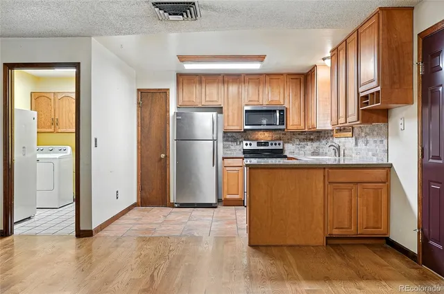 a kitchen with stainless steel appliances granite countertop a refrigerator a stove a sink and a microwave