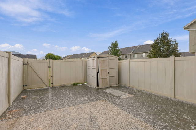 1041 South 1850th Street West Springville, UT 84663 - Photo 27 of 35 Fenced outdoor area featuring a double gate, paved surface, and a built-in storage shed