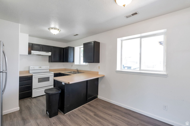 2013 West 460 South Provo, UT 84601 - Photo 20 of 24 Kitchen featuring dark cabinetry, light-toned countertops, wood-finish flooring, white appliances, and a window
