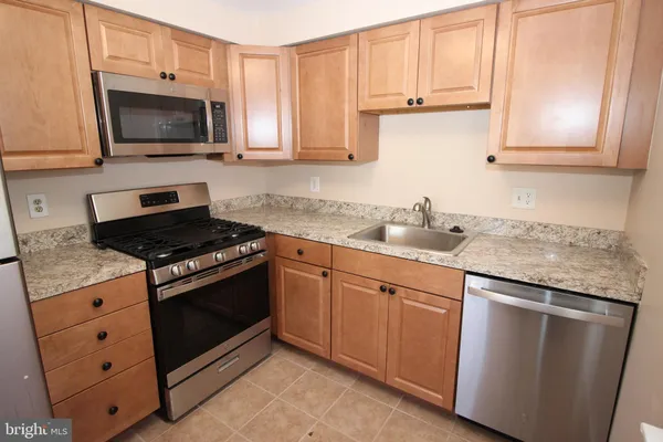 a kitchen with granite countertop a sink stove and microwave