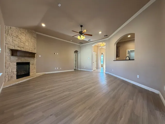 a view of an empty room with wooden floor fireplace and a window