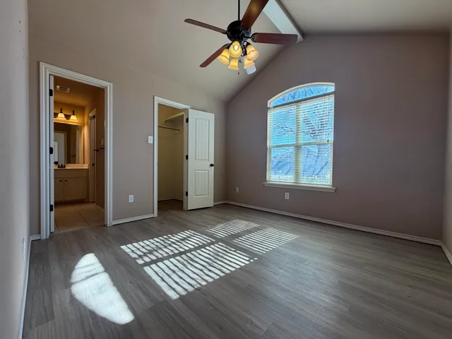 an empty room with wooden floor closet and windows
