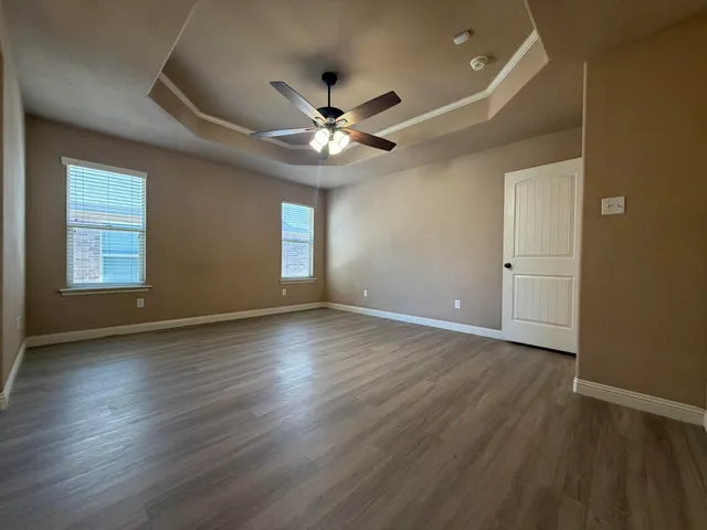 a view of an empty room with window and wooden floor