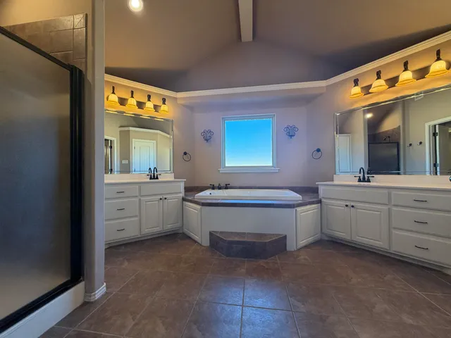 a spacious bathroom with a double vanity sink a mirror a bathtub and a vanity
