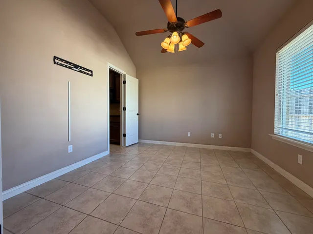 an empty room with windows and chandelier fan