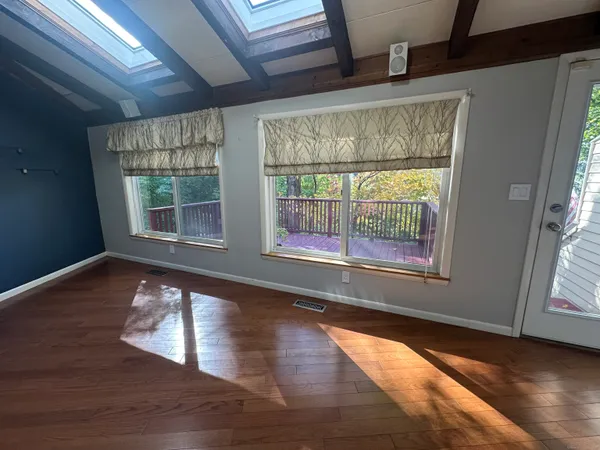 a view of an empty room with wooden floor and a window