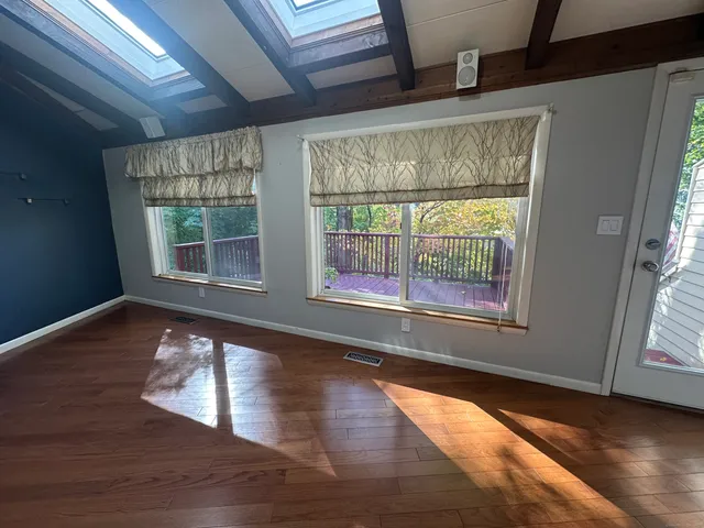 a view of an empty room with wooden floor and a window