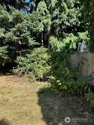 a view of an empty room with wooden floor fireplace and a window