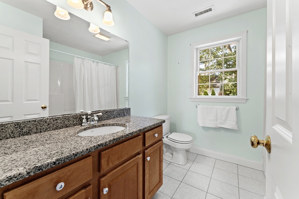 77 Hawthorne Road Waltham, MA 02451 - Photo 16 of 27 a bathroom with a granite countertop sink a toilet a mirror a window and vanity