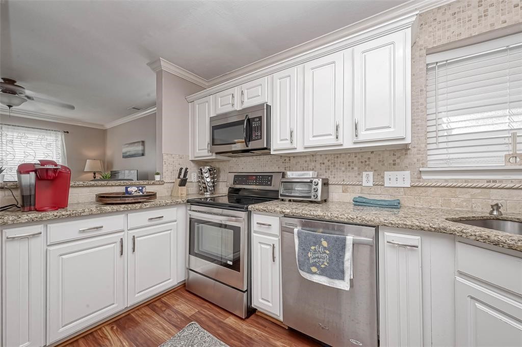 1204 Andrews Street Houston, TX 77019 - Photo 6 of 15 a kitchen with stainless steel appliances granite countertop a sink and cabinets with wooden floors