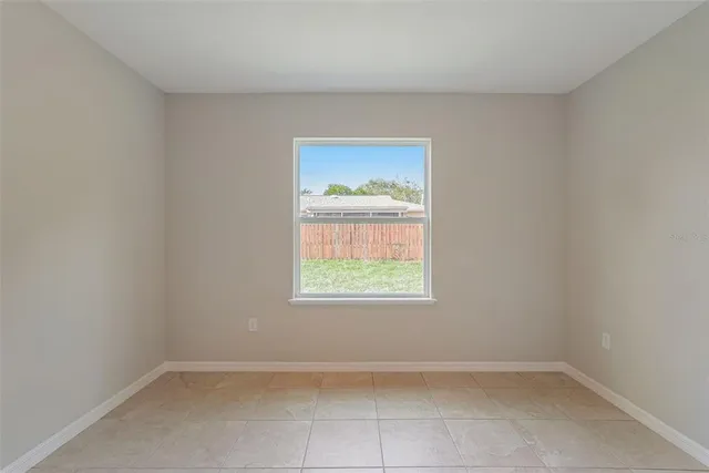 a view of an empty room with a kitchen and a window