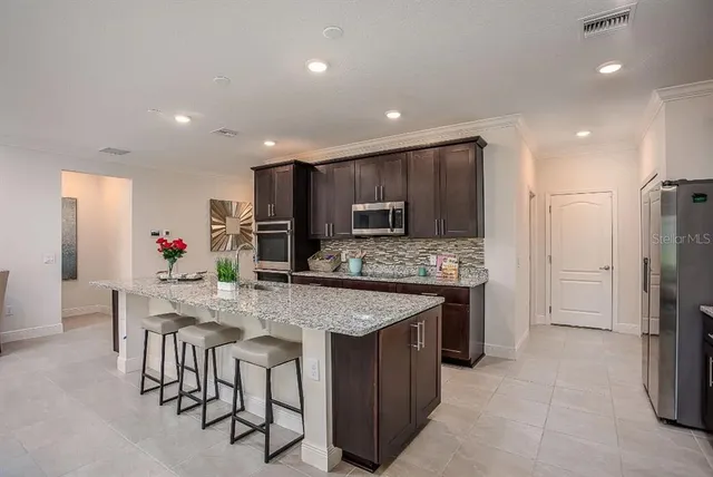 a kitchen with stainless steel appliances kitchen island granite countertop a stove refrigerator and cabinets