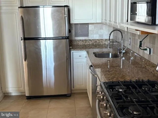 a kitchen with granite countertop a refrigerator and a sink