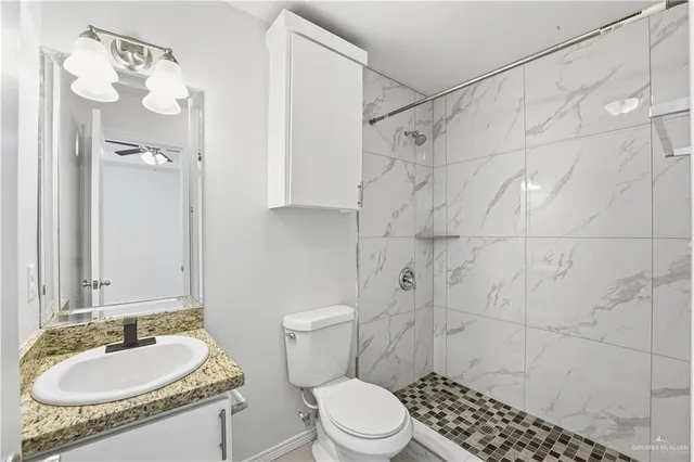 a bathroom with a granite countertop sink toilet a mirror and shower
