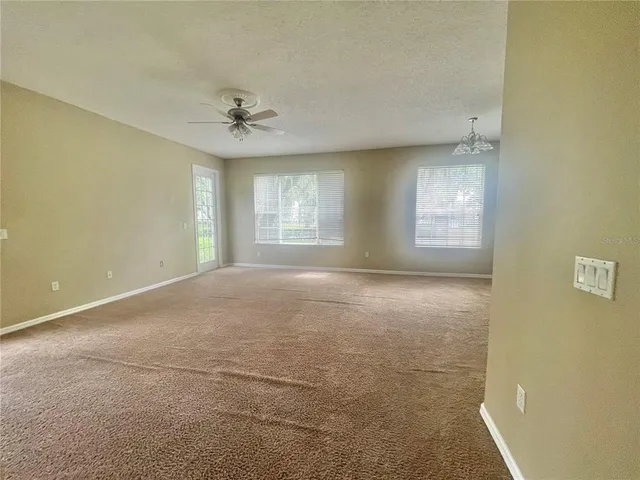 an empty room with windows and ceiling fan view