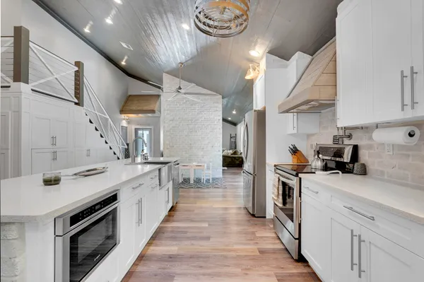 a kitchen with a sink dishwasher stove and white cabinets with wooden floor