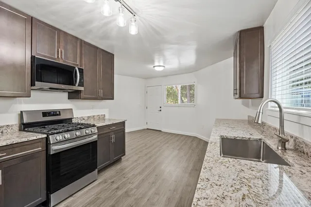 a kitchen with granite countertop a sink wooden floor and stainless steel appliances