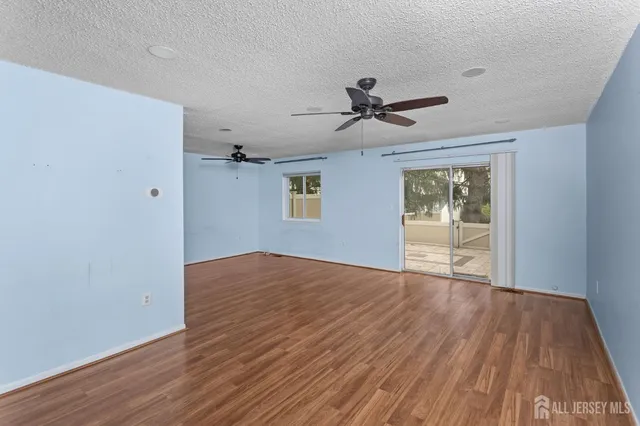 a view of empty room with wooden floor and ceiling fan